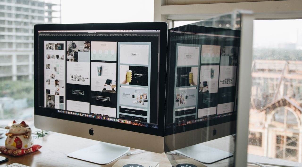 Deux écrans sur un bureau, montrant une conception web dans un environnement de bureau moderne.